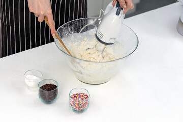 Closeup shot of woman in an apron  mixing batter in a clear glass bowl with an electric mixer.