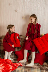 Little sisters girls on eve Christmas fighting with pillows at Christmas interior