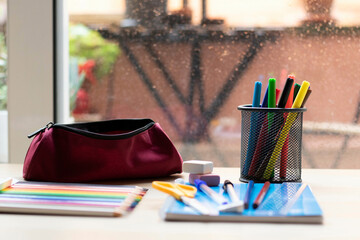 School supplies on a table. Pencils, markers, a ruler, erasers, a notebook, a pen, erasers, and a...