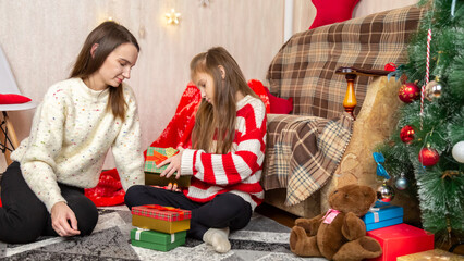 Happy mother and daughter opening christmas gift at home