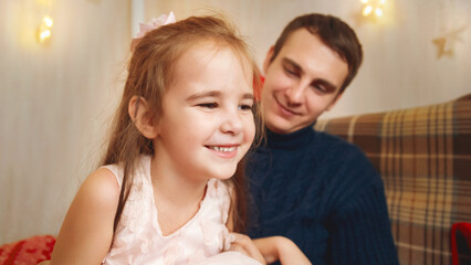 Father and daughter playing together in front of the Christmas tree