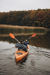 A back view of canoeists starting a trip on a calm autumn river in the middle of a forest in Ukraine