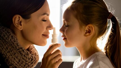 Mother applying nasal spray to her little daughter's nose to treat a cold or allergy for health care routine - Powered by Adobe