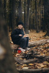 a little girl enjoys a meal at an autumn picnic sitting in the forest between the trees