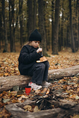a little girl enjoys a meal at an autumn picnic sitting in the forest between the trees
