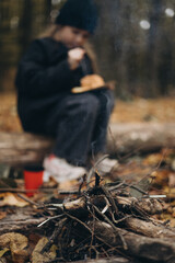 a little girl enjoys a meal at an autumn picnic sitting in the forest between the trees