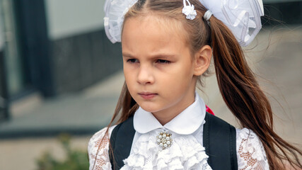 Close up portrait of happy cute junior girl smiling to camera while standing outdoor at schoolyard....