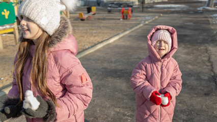 Two little girls playing on the playground on a winter day