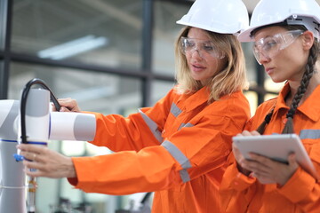 Female engineers checking or maintenance electronic in AI Robot, robot arm in the manufacturing...