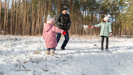 Little girls with her grandfather having fun on snowy winter day