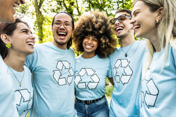 Multi ethnic group of volunteers cleaning up a forest together - Happy team of environmental activists smiling together outdoors - Environmental protection and non profits organization concept