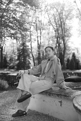 a woman dressed in a spring jacket, pants and sunglasses poses for a photo while walking in the...