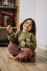 Joyful Child Sitting on Wooden Floor
