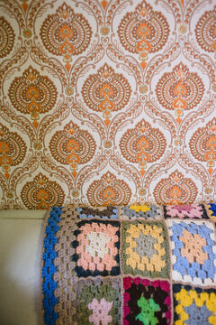 Fototapeta Crochet blanket draped over couch with wallpapered wall