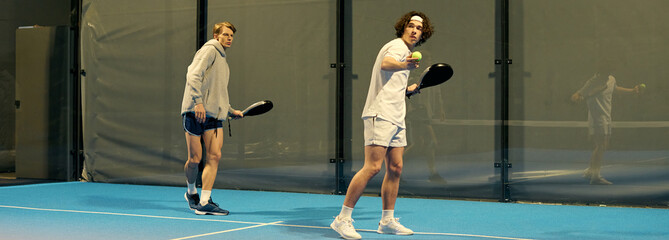 Young sportsmen engage in competitive padel match at indoor court