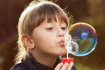 Little girl inflates a big bubble.