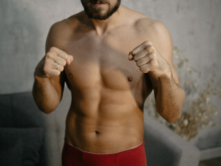 A young attractive man trains boxing at home after work.