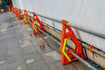 Bright Orange Construction Barriers with Reflective Panels on Wet Pavement in Urban Area
