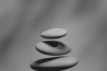 grey stones delicately balanced atop one another against a blurred grey backdrop, serene...