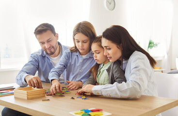 Happy friendly funny active family at home enjoy playing carefully wood cube board game together,...