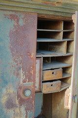 Rustic rusty Vintage Safe with Open Doors in Industrial Setting. Detailed image of an old, weathered metal safe revealing its worn inner compartments. Ideal for historical contexts, antique themes, or