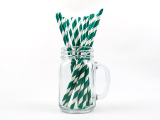 Green and white striped paper straws in a glass mason jar.