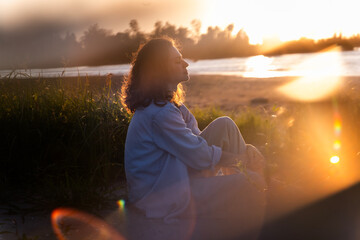 Summer portrait of a beautiful European woman at sunset on the river bank © olezzo