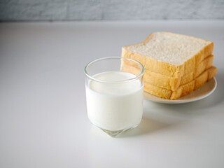 breakfast,Fresh milk in a glass and White sliced bread stacked on the white wooden table