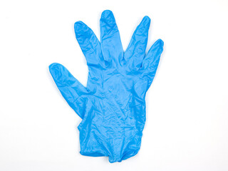 A single blue disposable medical glove laid flat isolated on white