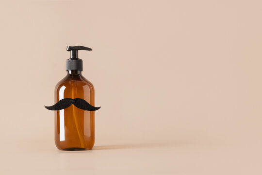 Brown cosmetic bottle for soap decorated black mustache on beige background. concept of men's care and spa wellness. Beard care. Creative design for barbershop. Copy space.