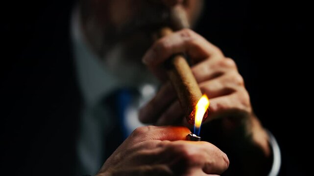 Close-up of man in business suit lighting cigar, enjoying the act of smoking