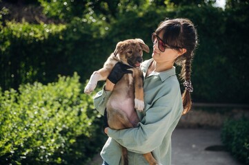 Woman is standing and holding cute dog
