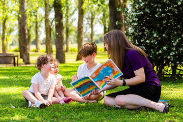 allied health professional speech therapist reading book to young children outside