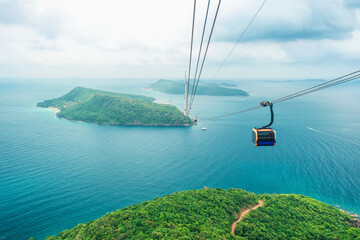 Cable car cabin gliding over turquoise sea and green tropical island. Longest Hon Thom cable car...