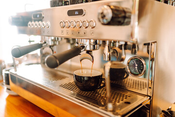 Espresso machine brews coffee and hot coffee pours into mug. Cozy coffee shop prepares aromatic drink for customers. Drink concept, barista and coffee shop. Small business.