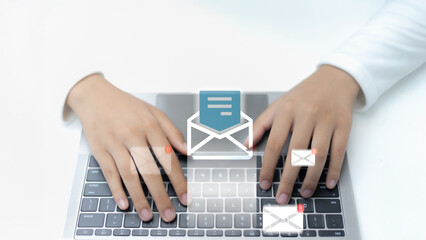 Close-up of hands typing on a laptop keyboard with email icons and notification alerts. Concept of...