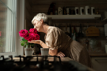A Woman Joyfully Enjoying Beautiful Fresh Roses in a Cozy and Inviting Kitchen Setting