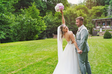 Beautiful wedding couple cuddling on their wedding day - hold hands together and are happy