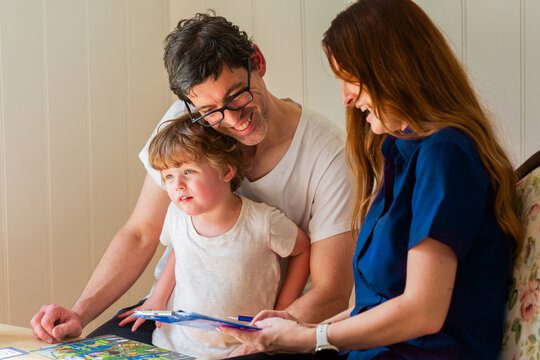 Parent with child talking with speech pathologist clinician holding paperwork during assessment