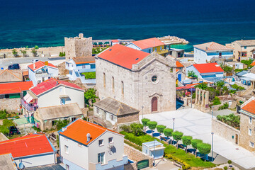 Aerial view of the coastal village of Razanac on the Paklenica Riviera in Croatia, showing traditional red-roofed houses, clear Adriatic waters, and views toward the Velebit mountain range