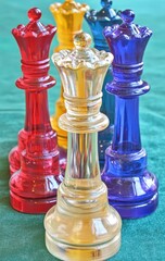 Colorful, translucent chess queens on a teal surface