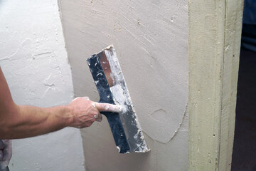 A man plastering a wall with a spatula. Apartment renovation