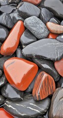 Close-up of various colored stones, predominantly dark gray/black and vibrant orange/red