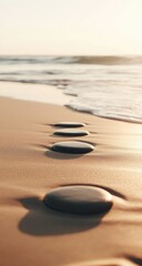 Four dark stones on a sandy beach, leading to the ocean waves