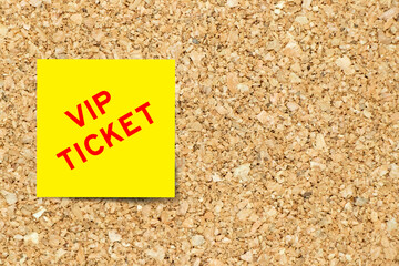Yellow note paper with word VIP ticket on cork board background with copy space