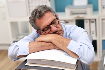 Office worker with glasses sleeps on a pile of files
