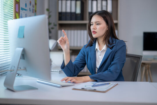 A woman is sitting at a desk with a computer monitor in front of her
