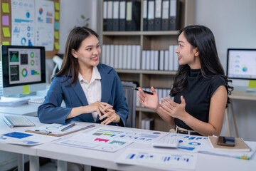 Two women are talking in a room with a lot of papers and books