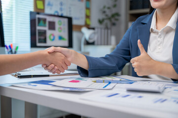 A woman shakes hands with another woman in a business setting