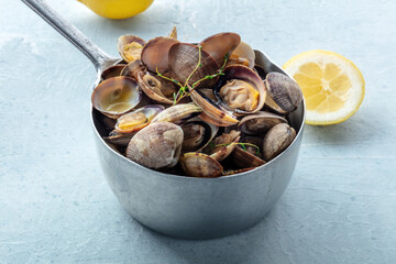 Vongole clams in a saucepan with thyme, lemon, and olive oil. Seafood sauce, Mediterranean cuisine